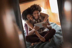 Couple sitting on bed in trailer home and using digital tablet